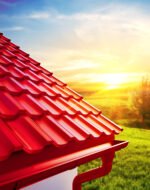 Raudonas modulinis stogas „Panorama“ su lietvamzdžiais prieš saulėtą kraštovaizdį. Plieninė stogo danga.